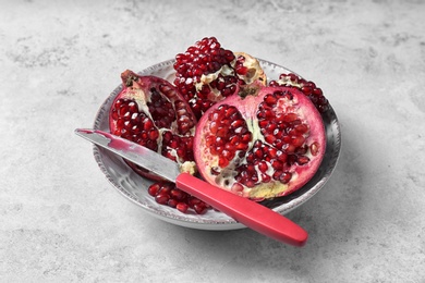 Photo of Plate with ripe pomegranates and knife on grey background