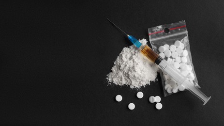 Photo of Powder, syringe and pills on black background, flat lay with space for text. Hard drugs