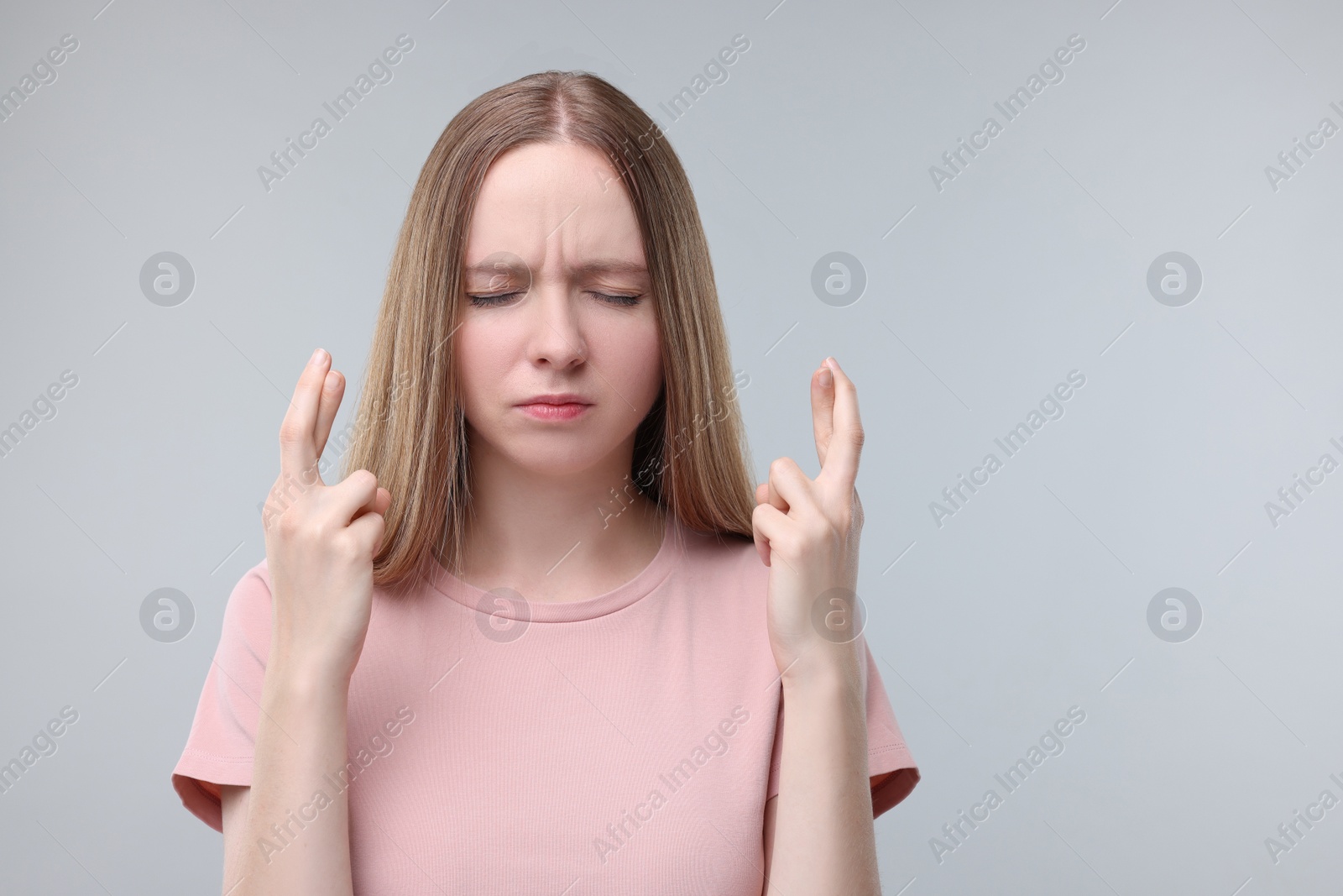 Photo of Woman crossing her fingers on grey background, space for text