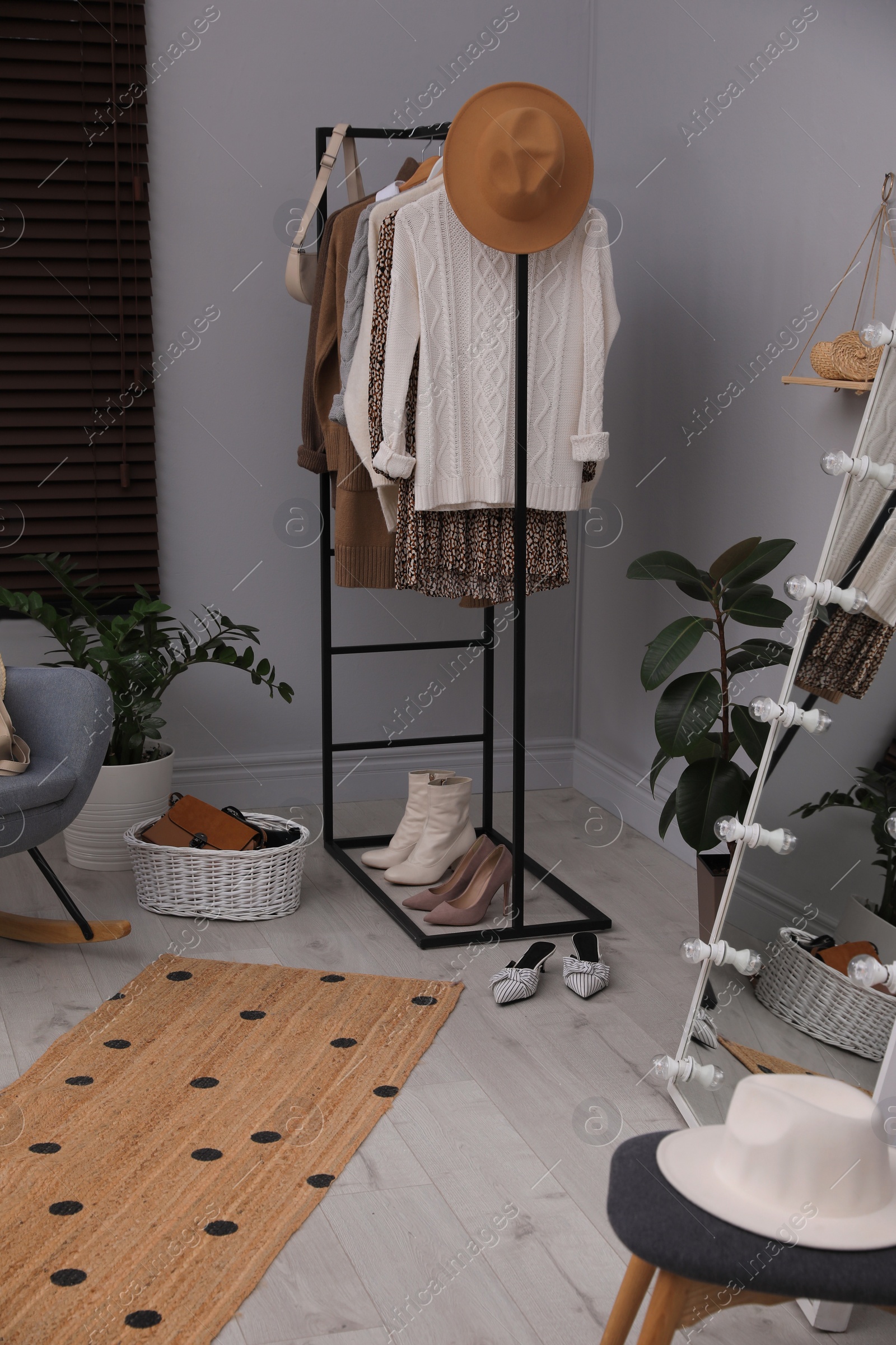 Photo of Rack with stylish women's clothes and shoes in dressing room