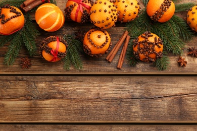 Photo of Flat lay composition with pomander balls made of fresh tangerines and cloves on wooden table, space for text