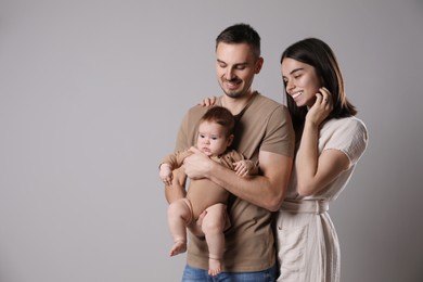 Happy family. Couple with their cute baby on grey background, space for text