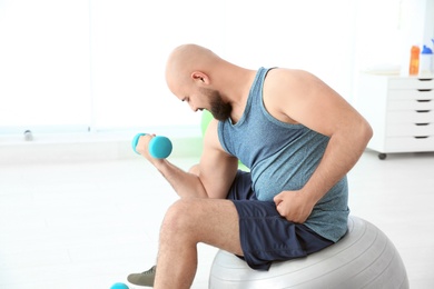 Overweight man doing exercise with dumbbell in gym