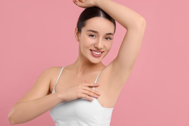 Photo of Beautiful woman showing armpit with smooth clean skin on pink background