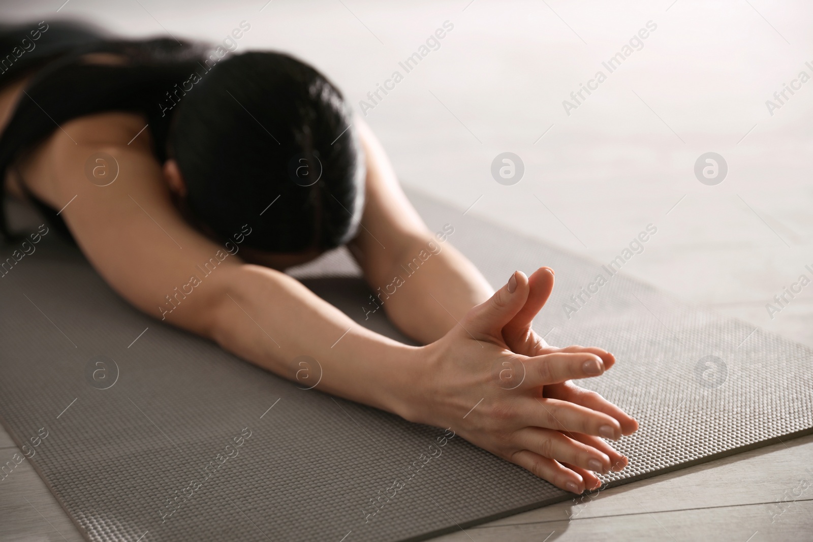 Photo of Young woman practicing extended child's asana in yoga studio, closeup. Utthita Balasana pose