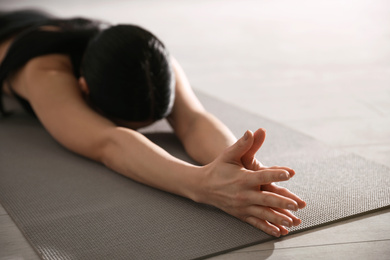 Photo of Young woman practicing extended child's asana in yoga studio, closeup. Utthita Balasana pose