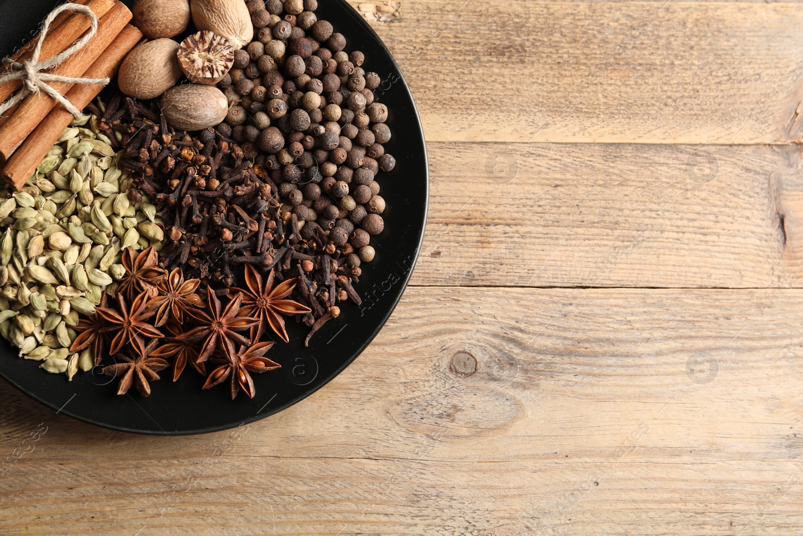 Photo of Different spices and nuts on wooden table, top view. Space for text