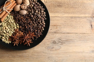 Different spices and nuts on wooden table, top view. Space for text