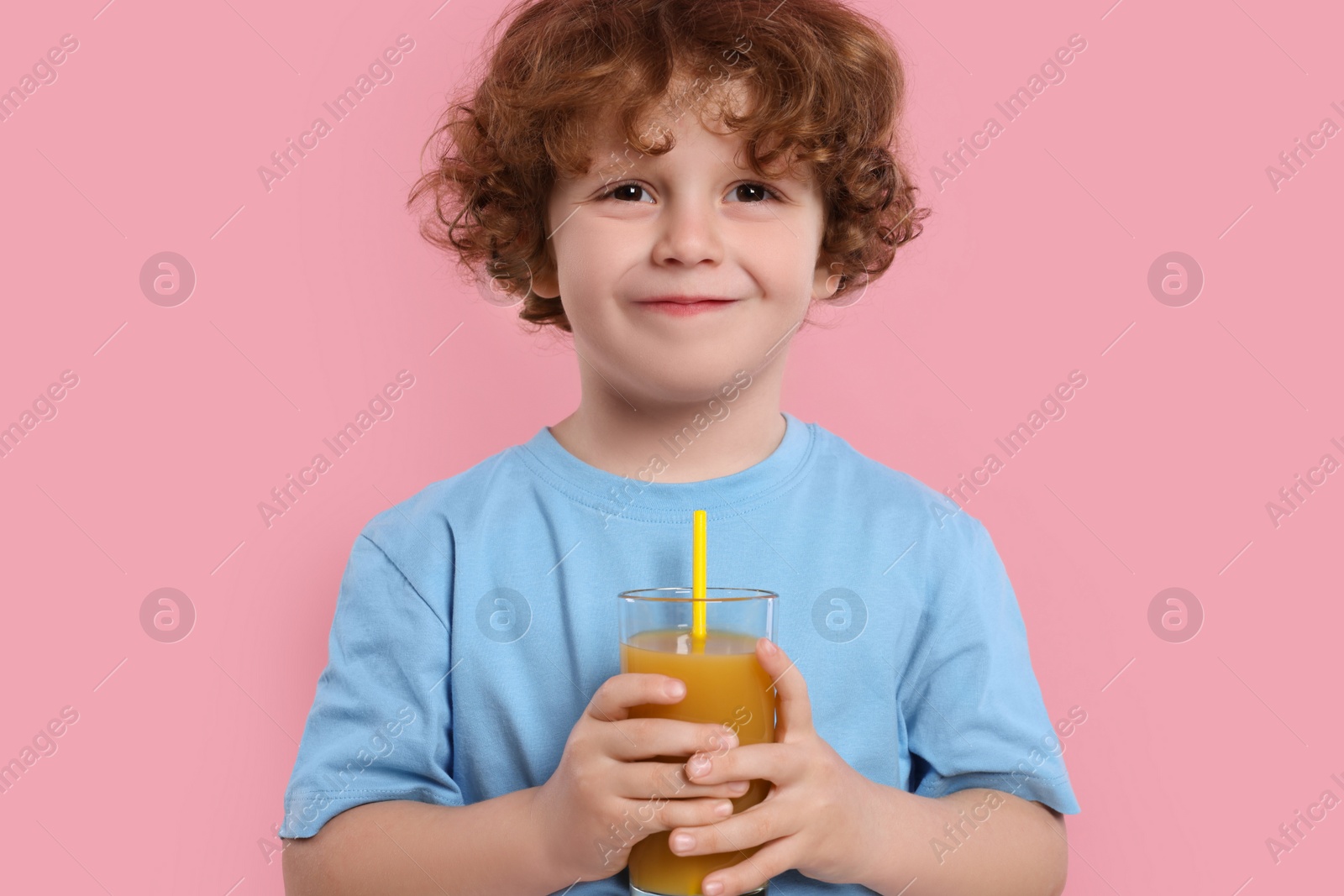 Photo of Cute little boy with glass of fresh juice on pink background