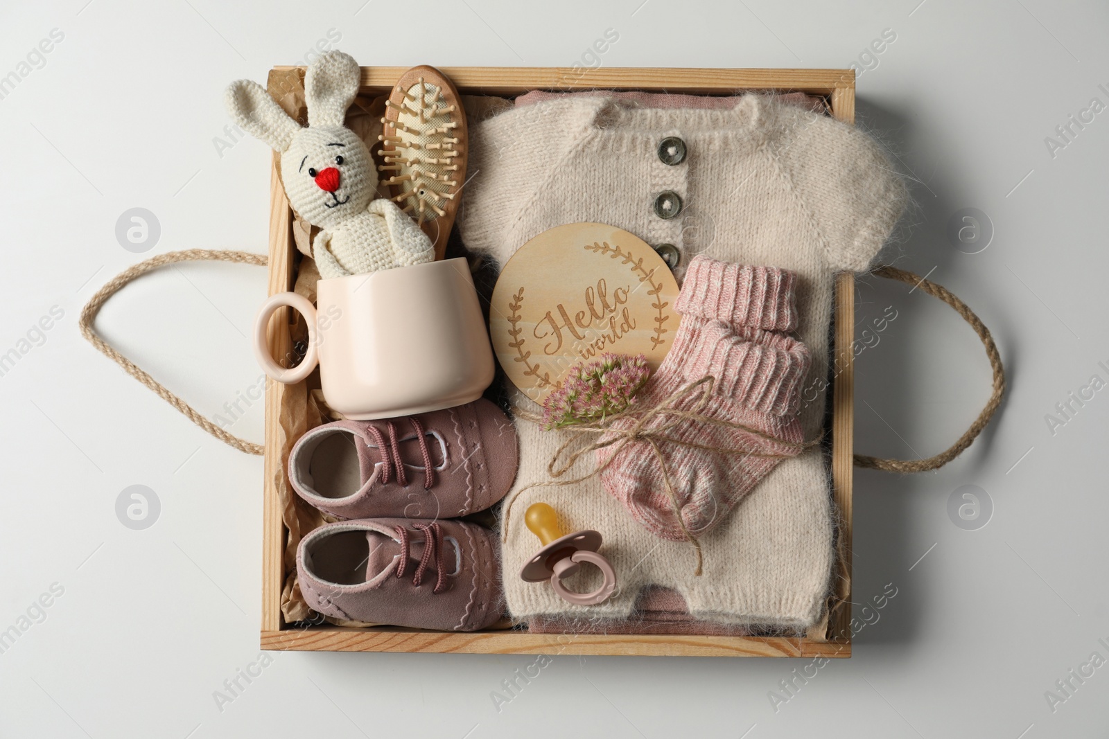 Photo of Box with baby clothes, shoes and accessories on light background, top view