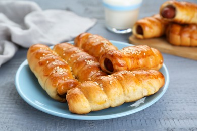 Delicious sausage rolls and milk on grey wooden table, closeup