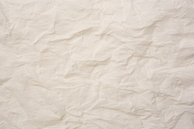 Photo of Texture of crumpled beige paper as background, closeup view