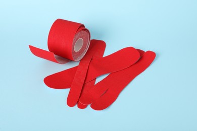 Photo of Red kinesio tape roll and pieces on light blue background