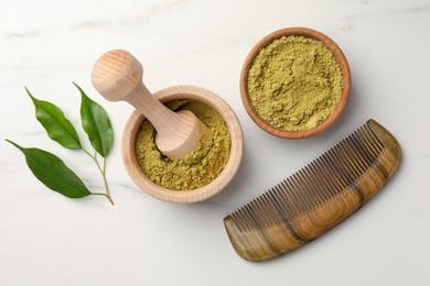 Photo of Mortar of henna powder, comb and green leaves on white marble table, flat lay. Natural hair coloring