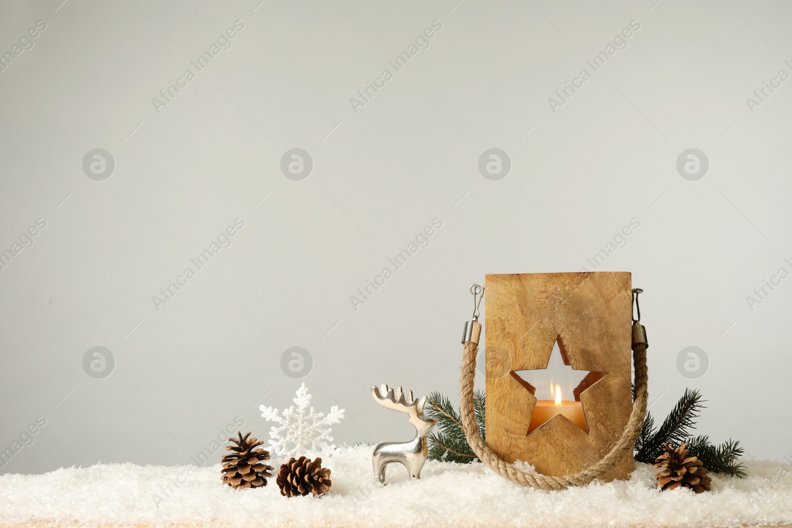 Photo of Composition with wooden Christmas lantern on snow against light grey background, space for text