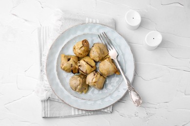 Delicious pickled artichokes served on white textured table, flat lay