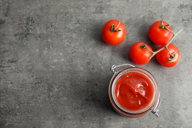 Jar with homemade tomato sauce, fresh vegetables and space for text on table, top view