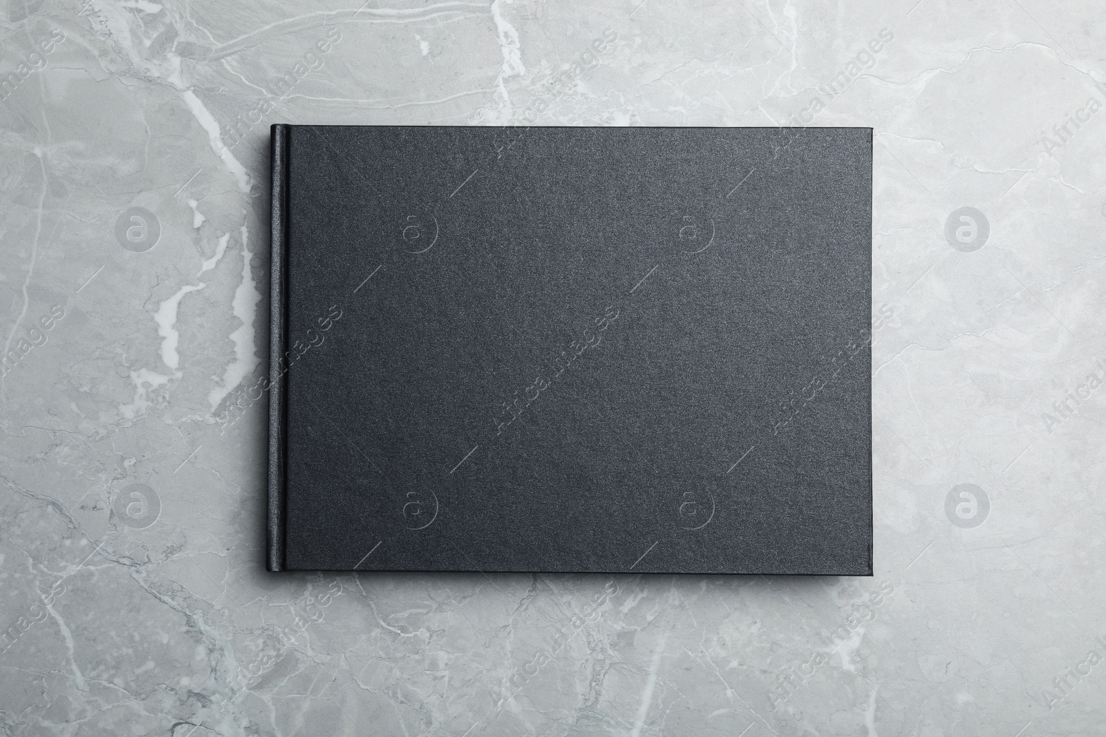 Photo of Stylish black notebook on marble table, top view