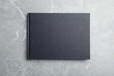Photo of Stylish black notebook on marble table, top view