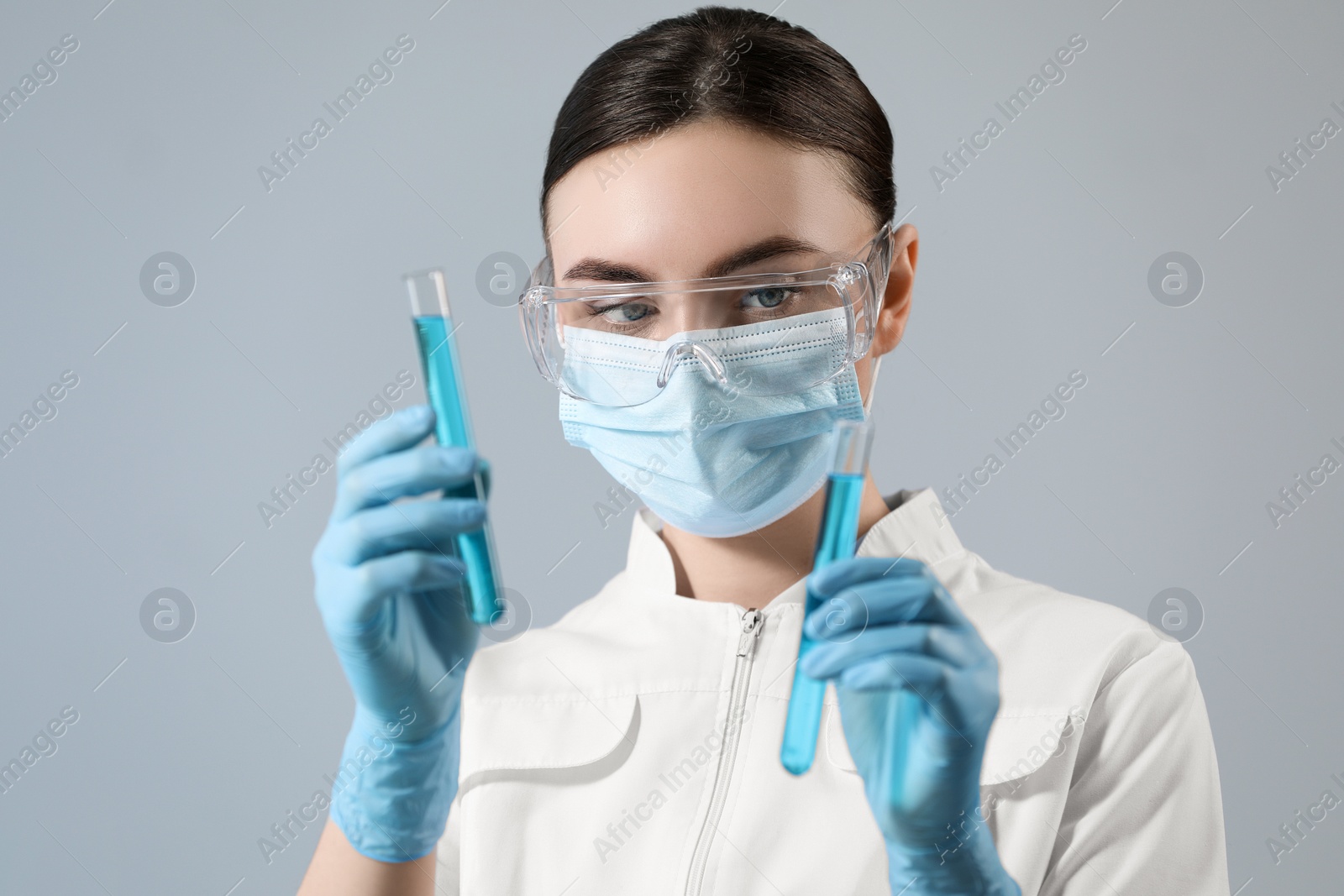 Photo of Scientist holding test tubes with samples on grey background