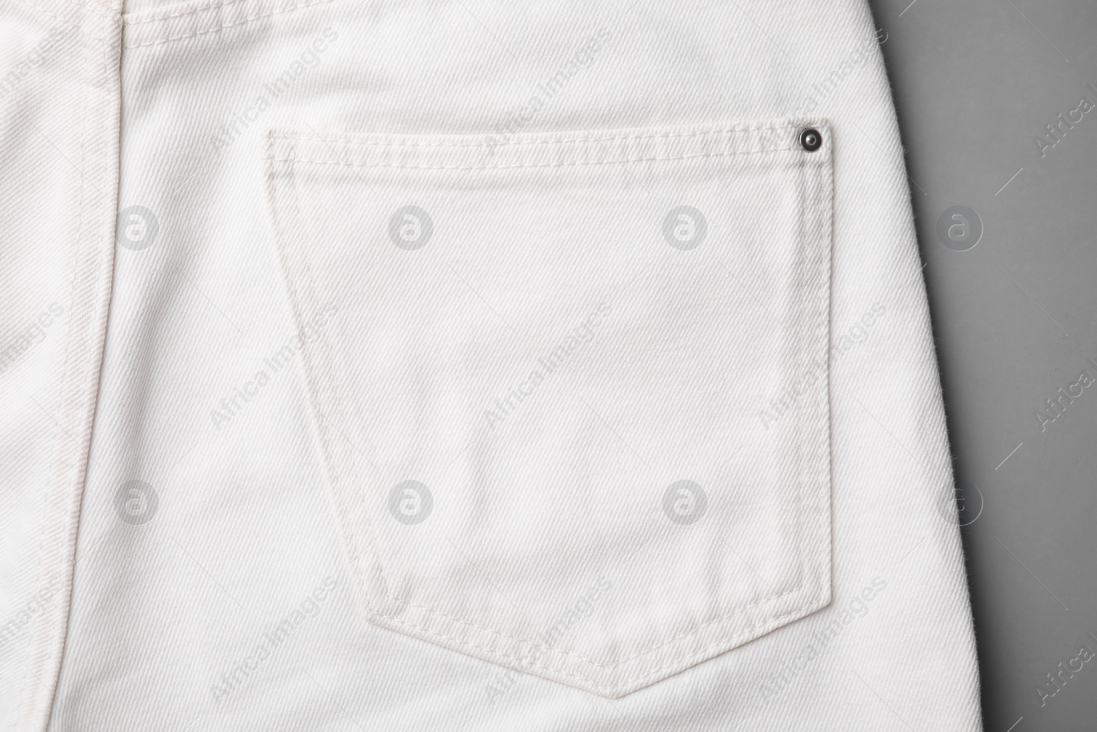 Photo of White jeans with pocket on grey background, top view