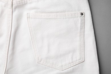 White jeans with pocket on grey background, top view