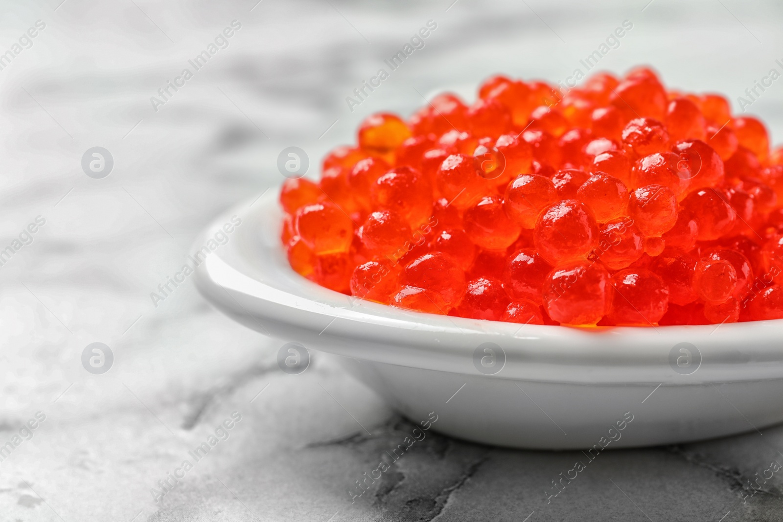 Photo of Dish with delicious red caviar on light background