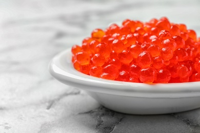 Photo of Dish with delicious red caviar on light background