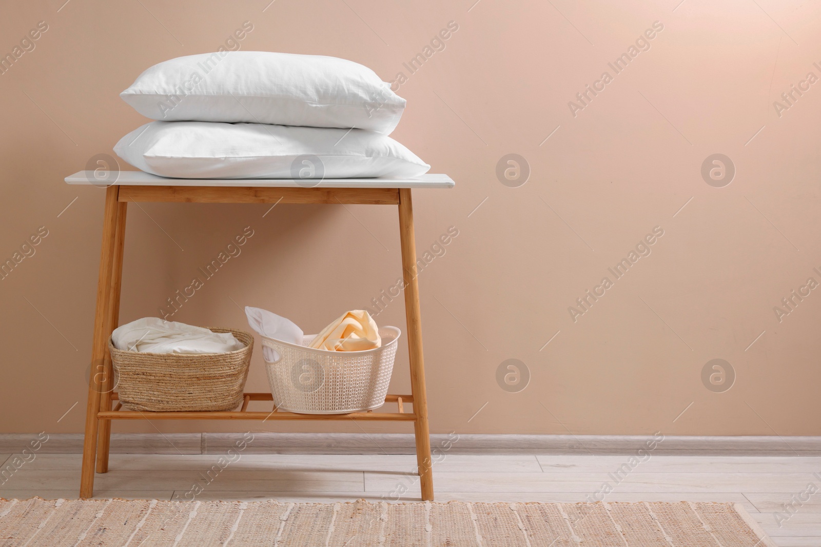 Photo of Soft pillows and laundry baskets near beige wall indoors. Space for text