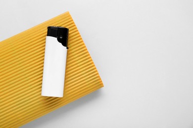 Photo of Stylish small pocket lighter with yellow corrugated fiberboard on white background, top view. Space for text