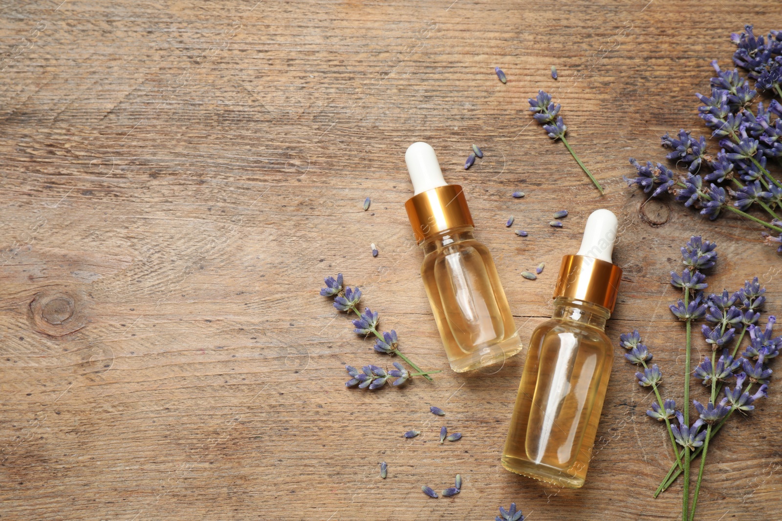 Photo of Flat lay composition with lavender flowers and natural essential oil on wooden table. Space for text