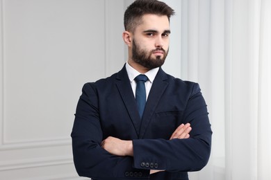 Photo of Handsome businessman in suit and necktie with crossed arms indoors