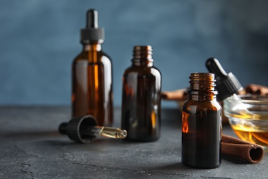 Photo of Composition with cinnamon essential oil on table against blue background