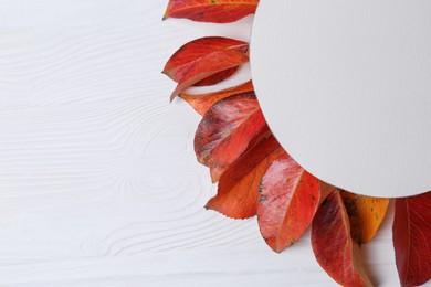 Photo of Flat lay composition with blank card and autumn leaves on white wooden table. Space for text