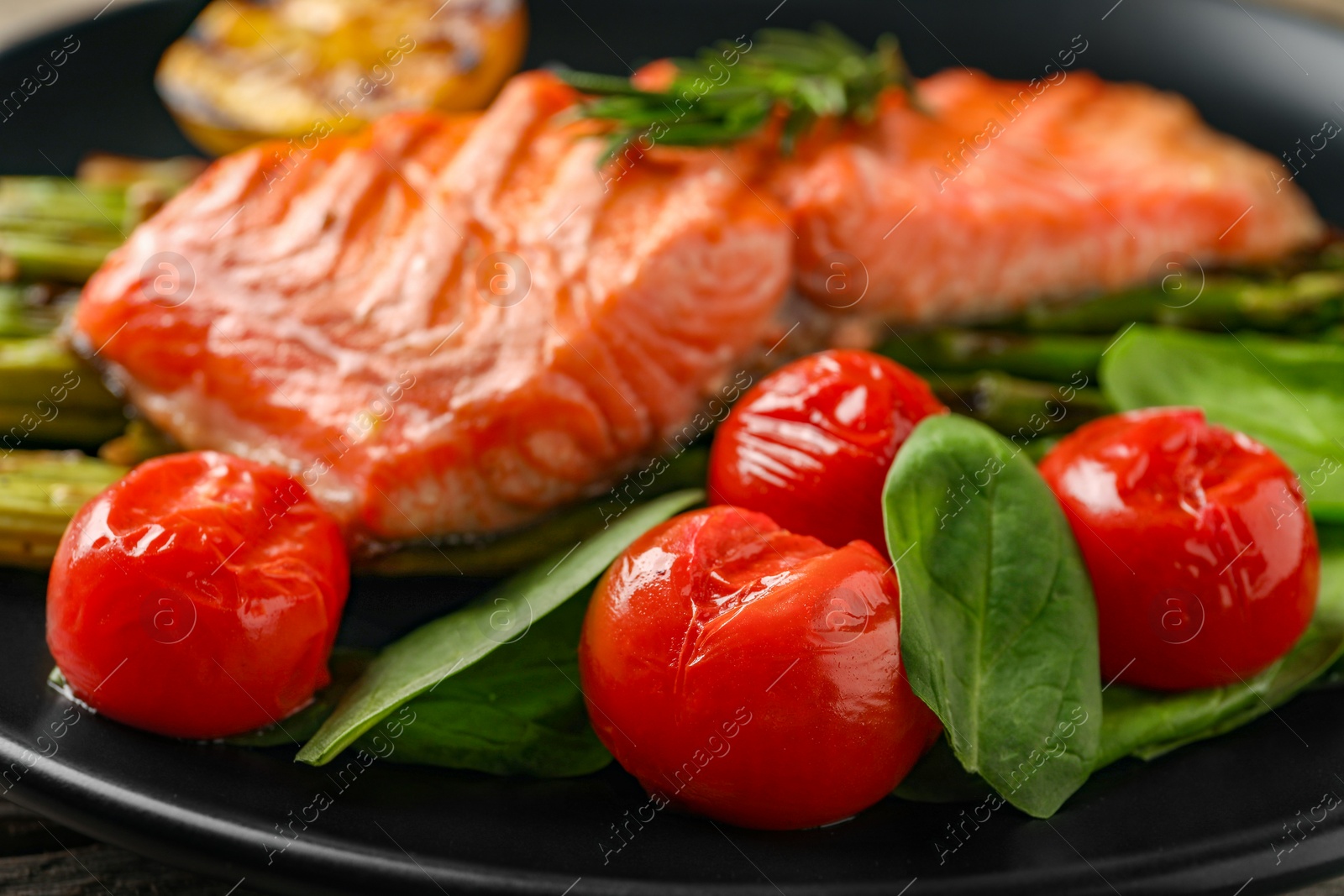 Photo of Tasty grilled salmon with tomatoes and spinach on plate, closeup