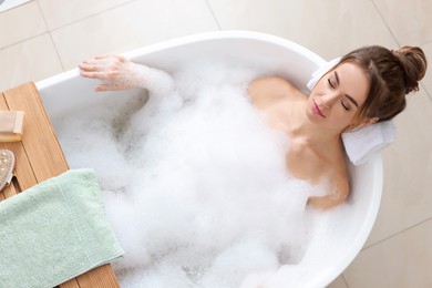Photo of Beautiful woman enjoying bubble bath at home, above view