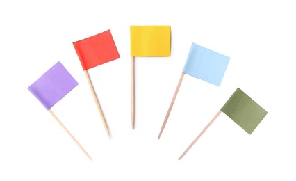 Set of toothpicks with small colorful paper flags on white background, top view