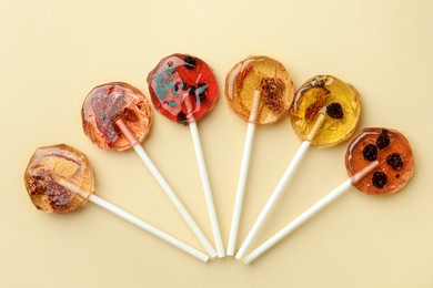 Photo of Sweet colorful lollipops with berries on beige background, flat lay