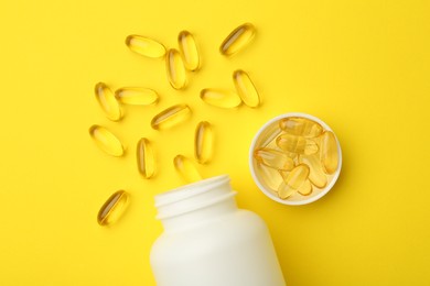 Photo of Softgel capsules, lid and bottle on yellow background, flat lay