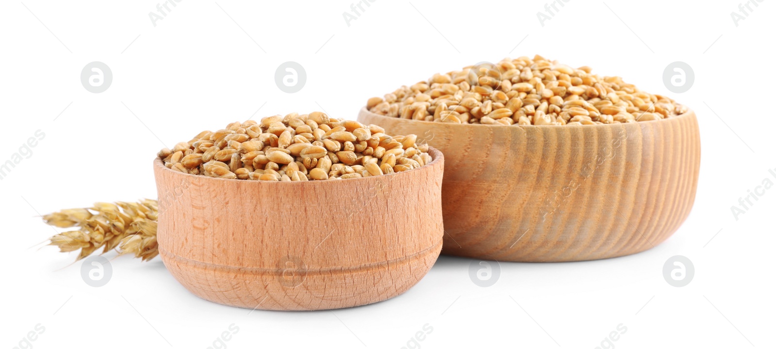 Photo of Wooden bowls with wheat grains and spikes on white background