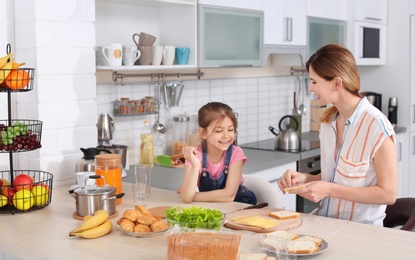 Photo of Housewife with her daughter preparing dinner on kitchen