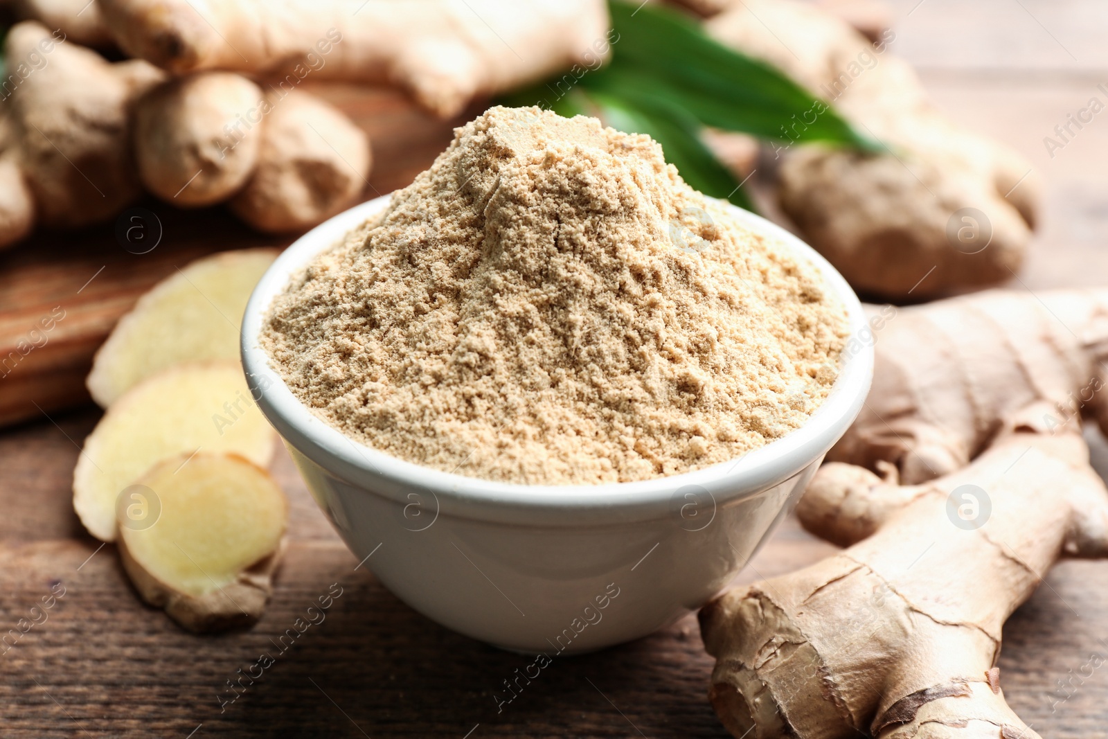 Photo of Dry ginger powder and fresh root on wooden table