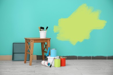 Image of Set with decorator's tools and paint on floor near turquoise wall