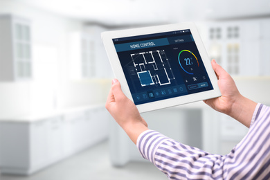 Image of Energy efficiency home control system. Woman using tablet to set indoor temperature, closeup