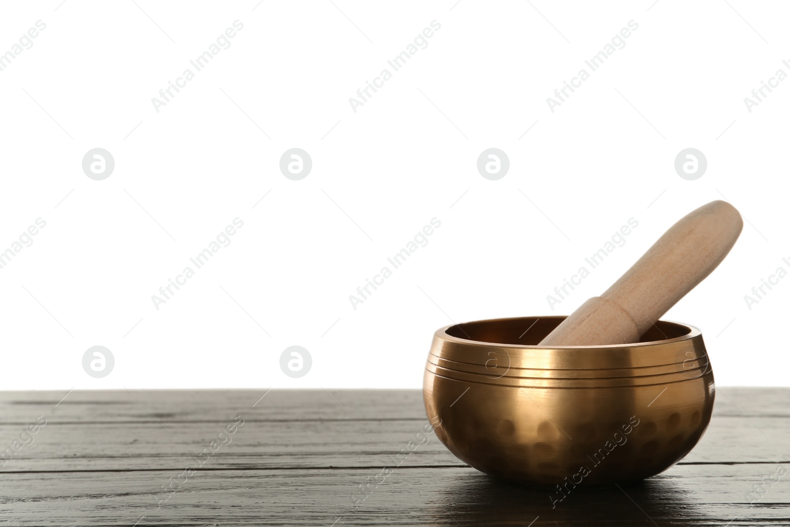 Photo of Golden singing bowl and mallet on wooden table against white background, space for text