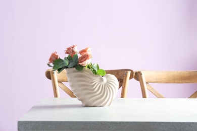 Vase with beautiful flowers as element of interior design on table in room