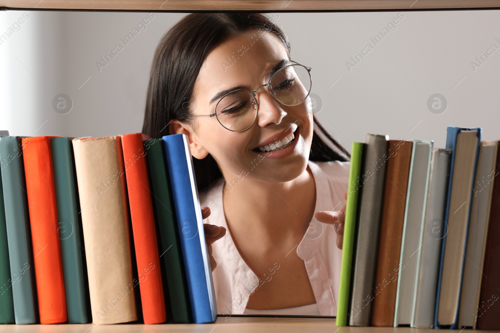 Photo of Woman searching for book on shelf in library