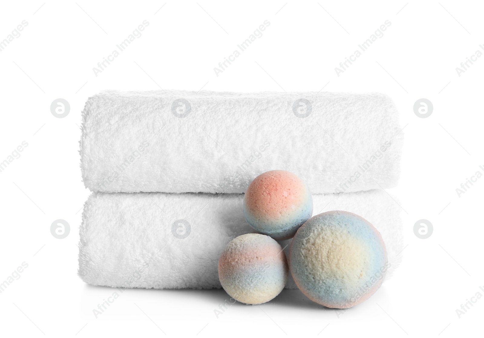 Photo of Stack of clean soft towels and bath bombs on white background