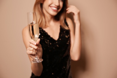 Beautiful woman with glass of champagne on color background, closeup