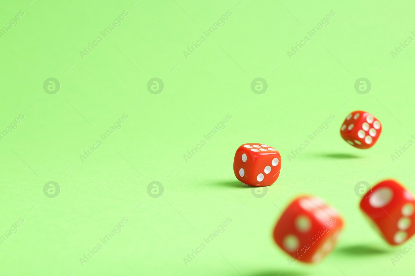 Photo of Many red game dices falling on green background. Space for text